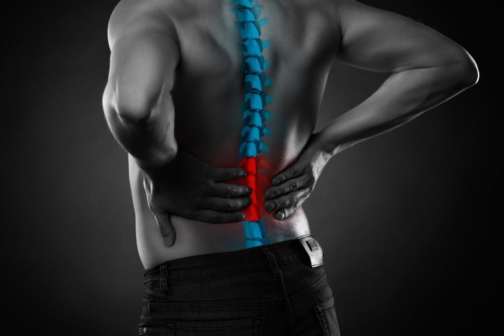 Person experiencing back pain due to Ankylosing Spondylitis.