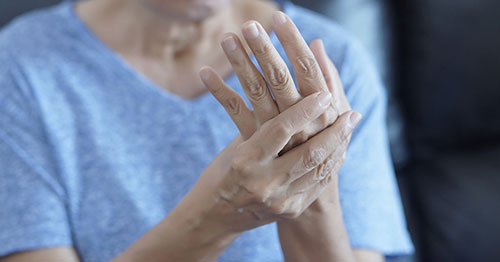 Person experiencing joint pain due to inflammatory arthritis.