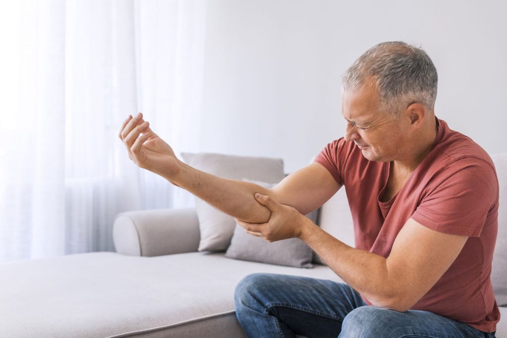 Person experiencing rheumatoid arthritis flare-up, holding their joints