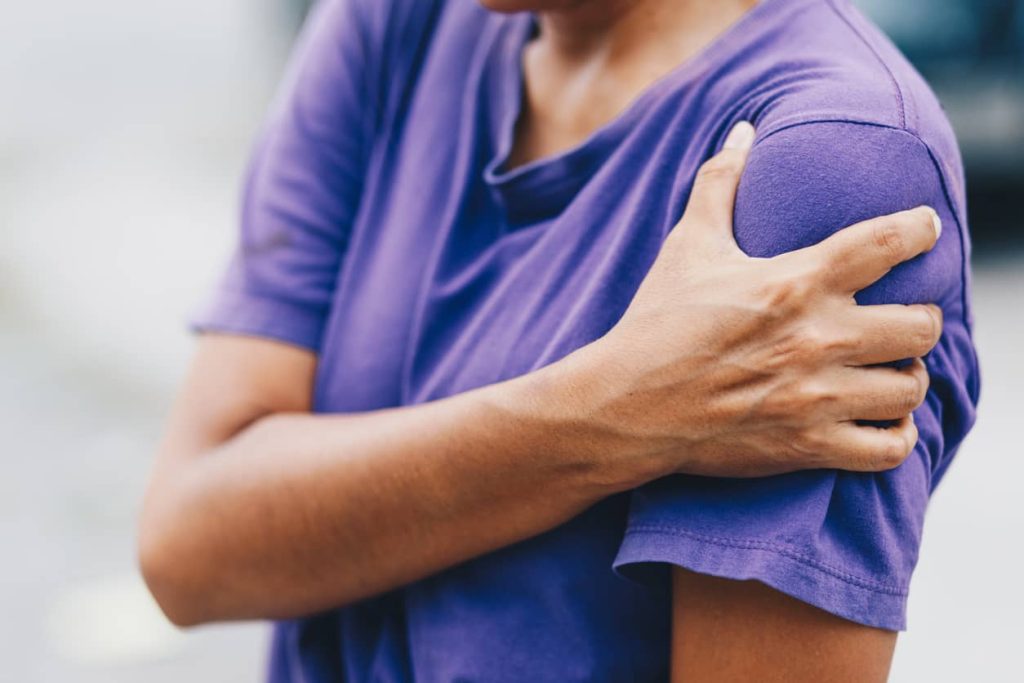 Person experiencing nerve pain, holding their arm.